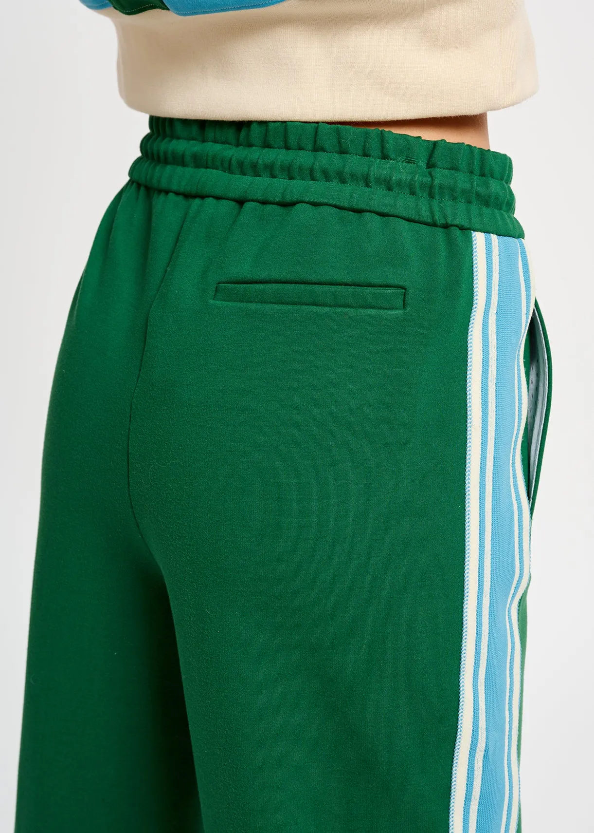 Green track pants with blue and off-white stripes