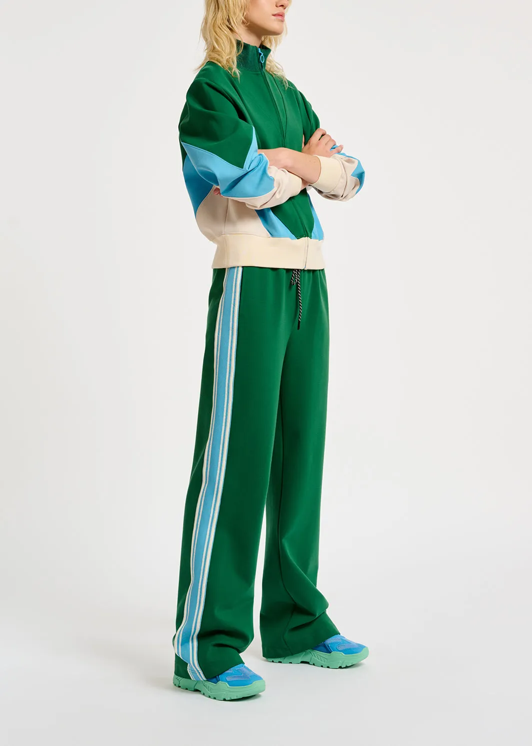 Green track pants with blue and off-white stripes