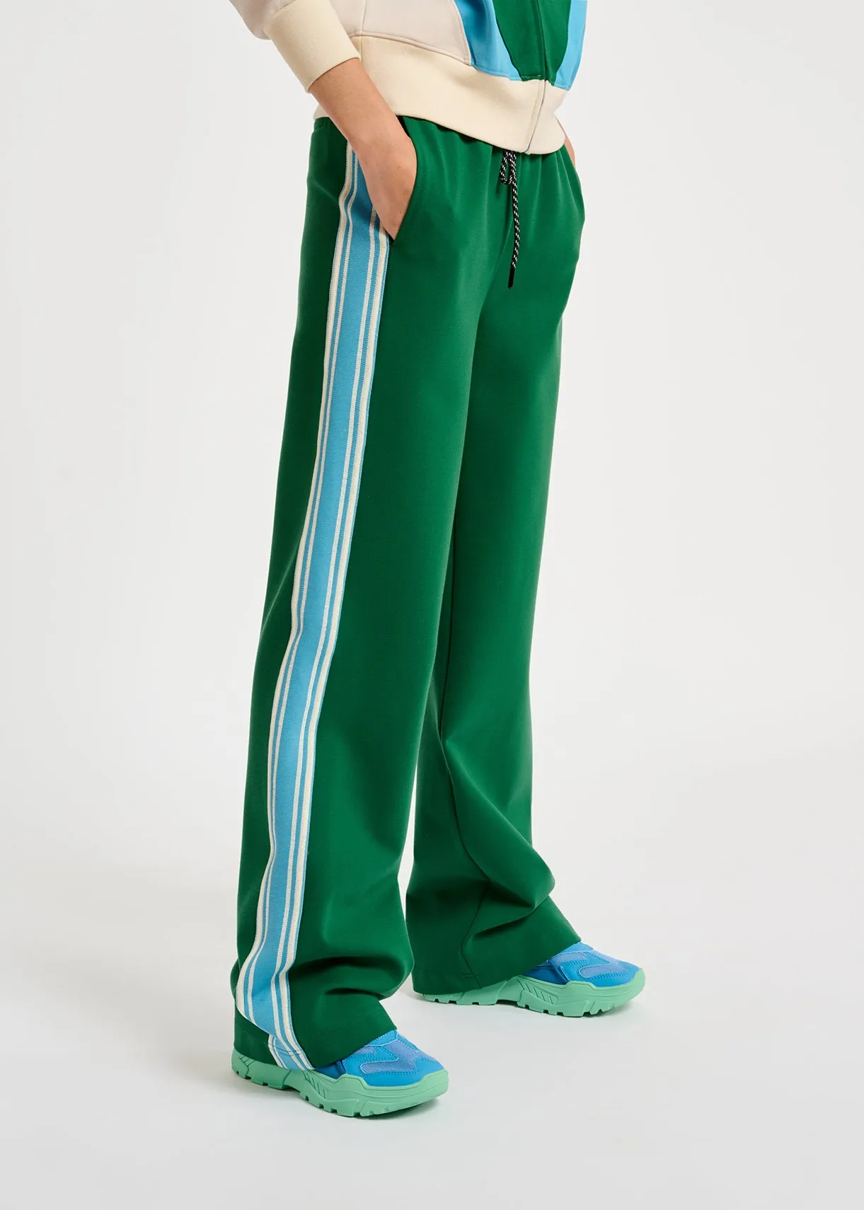 Green track pants with blue and off-white stripes