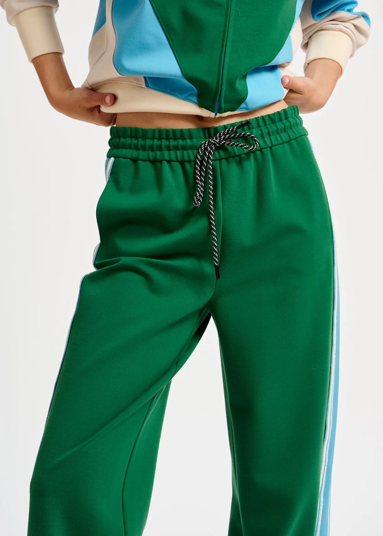 Green track pants with blue and off-white stripes